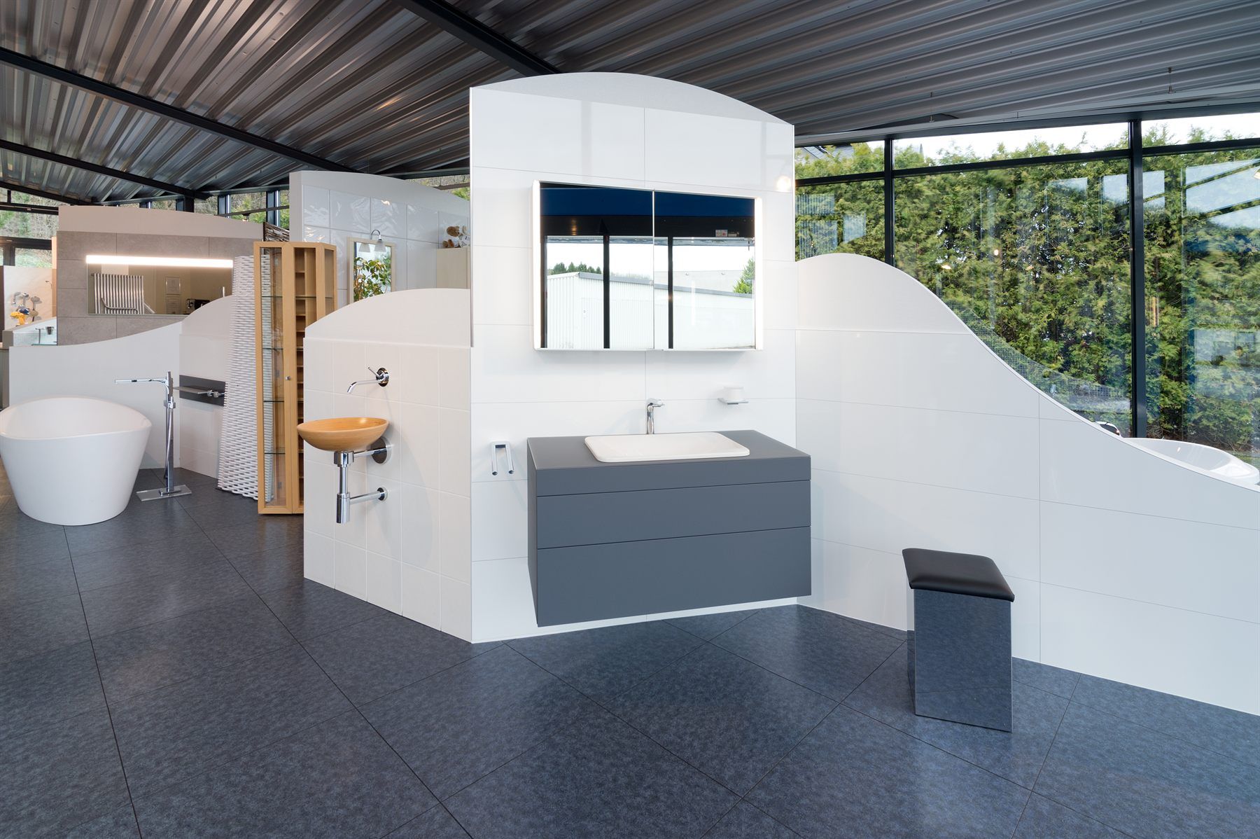 Ausstellungsbereich mit freistehender Badewanne, Waschtisch, Spiegel und Sitzhocker