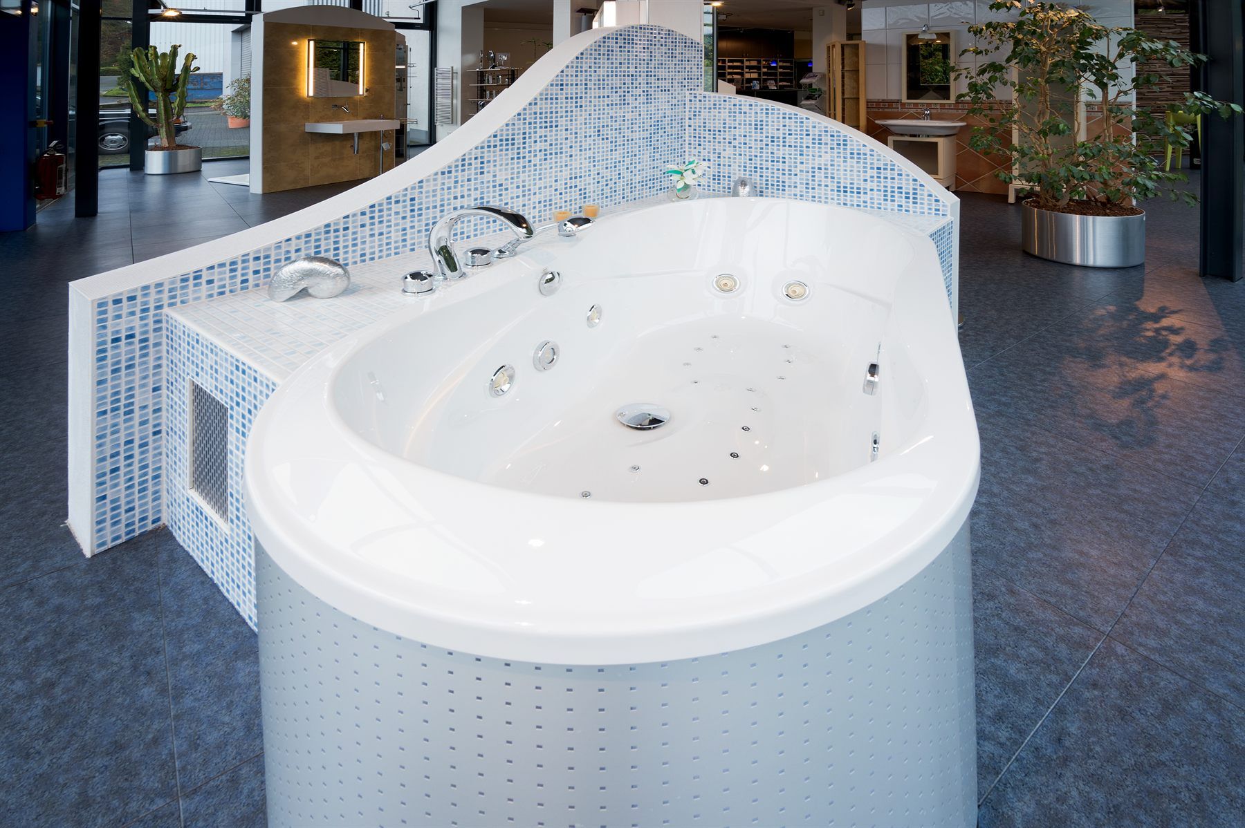 Whirlpool-Badewanne mit blauer Mosaikverkleidung im Ausstellungsraum